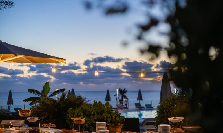 Outdoor dinner at sunset with a sea view.