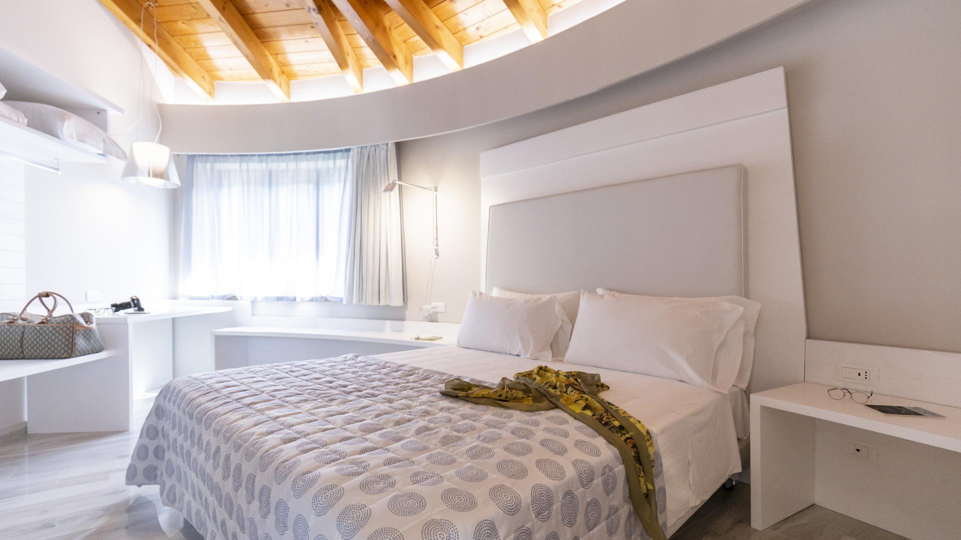 Modernes Zimmer mit Doppelbett, Holzdecke und weißen Möbeln.