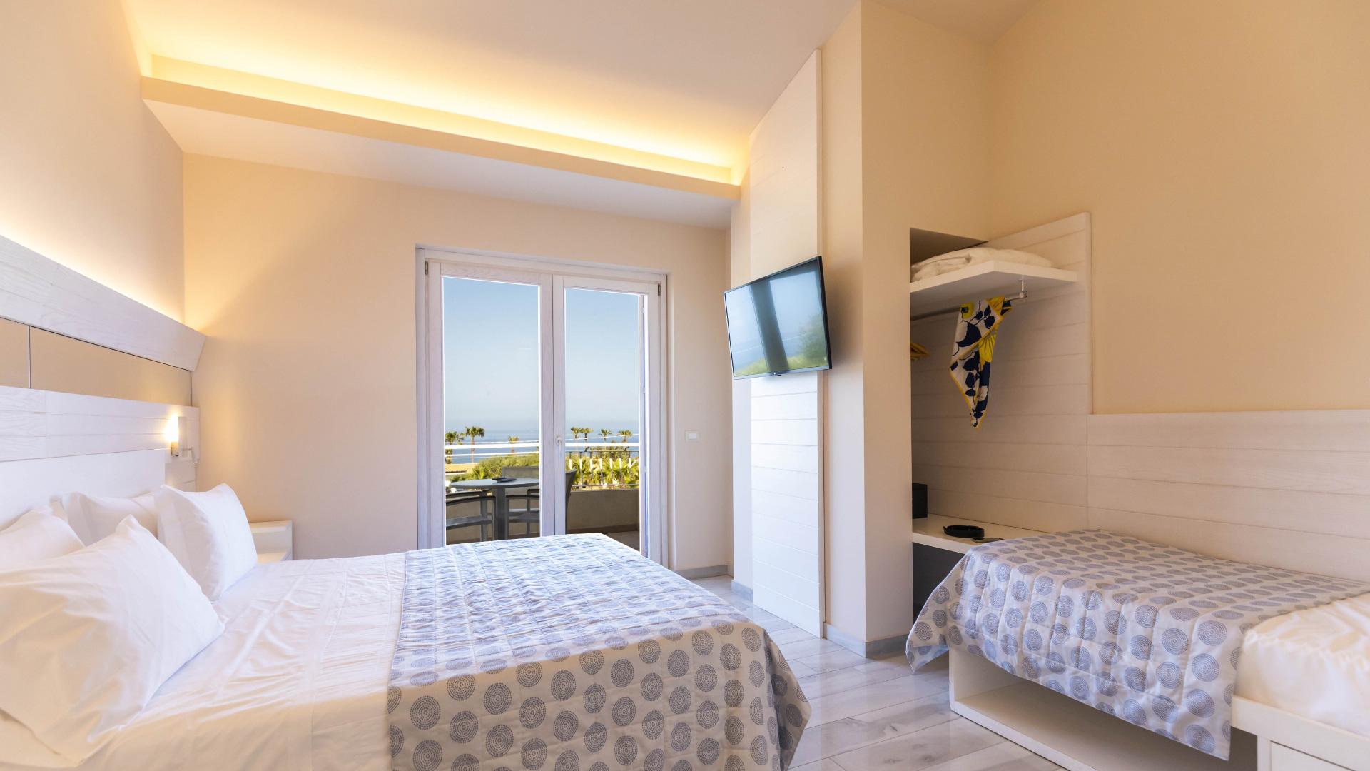 Bright room with sea view, double bed and single bed.