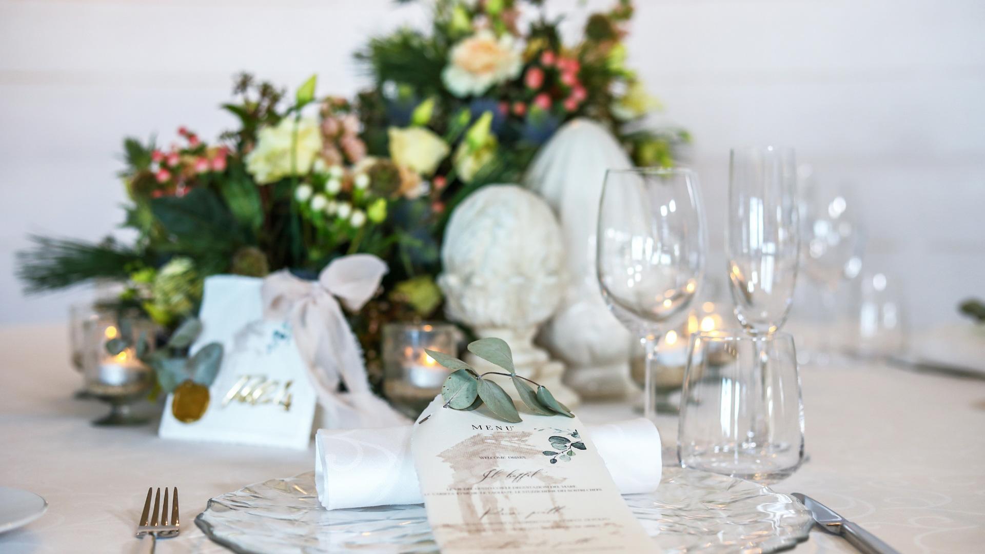 Elegant table with flowers, menu, and crystal glasses.