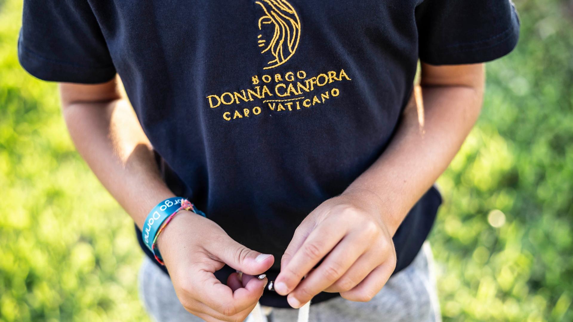 Person wearing Borgo Donna Canfora shirt, Capo Vaticano, and colorful bracelet.