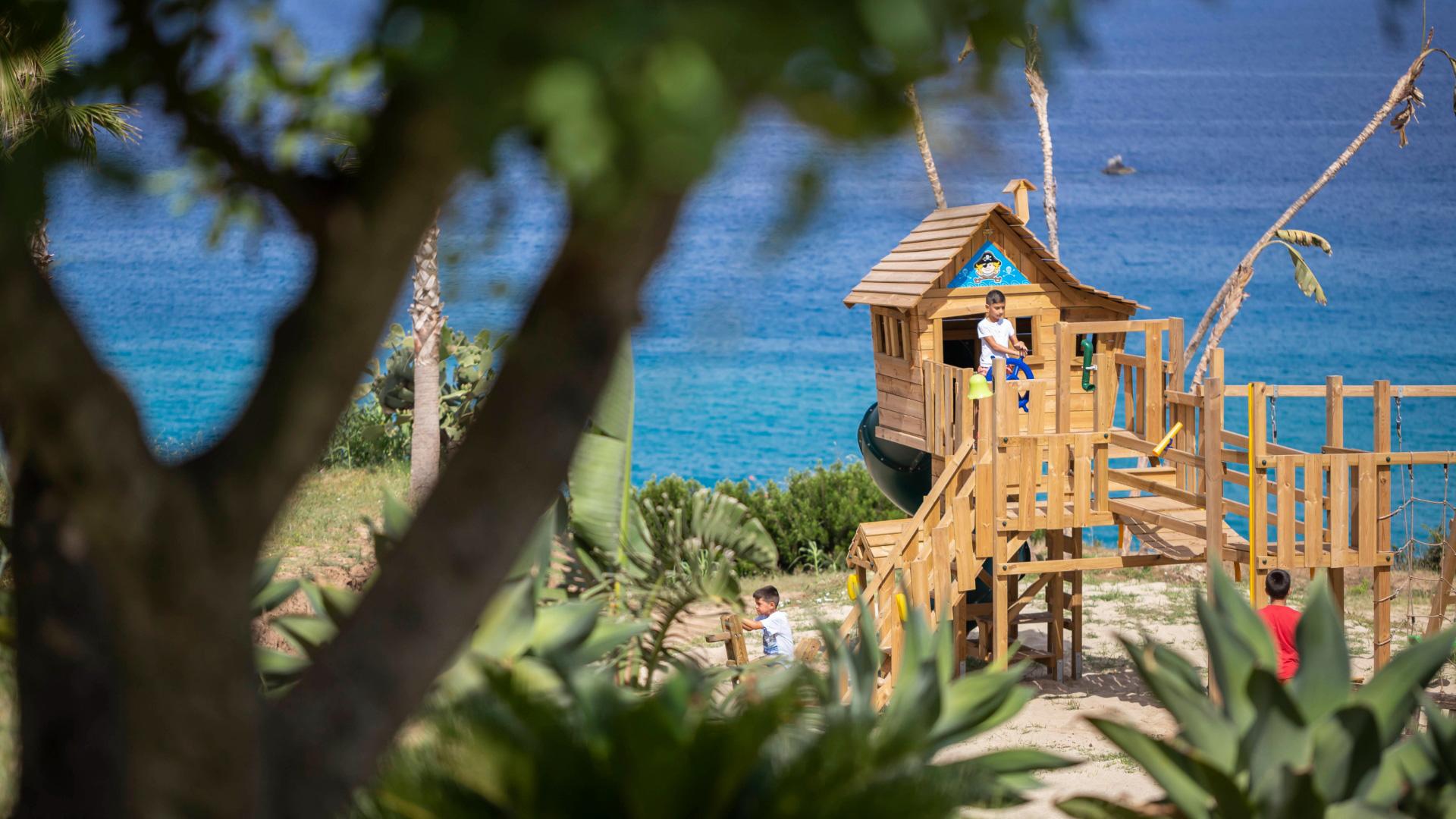Children playing in a treehouse by the sea.