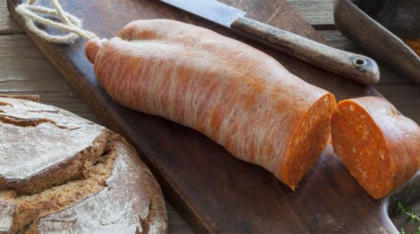 Soppressata calabraise avec pain et épices sur une planche en bois.