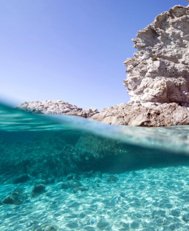 Crystal clear water and white rocks under a blue sky.