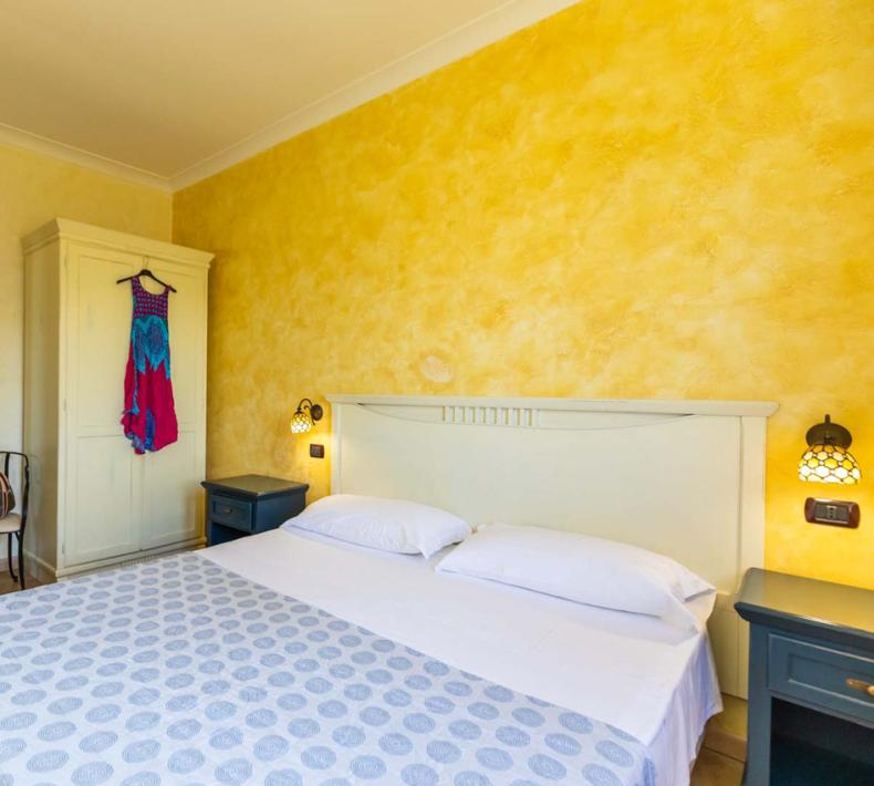 Camera da letto luminosa con pareti gialle e arredi classici.