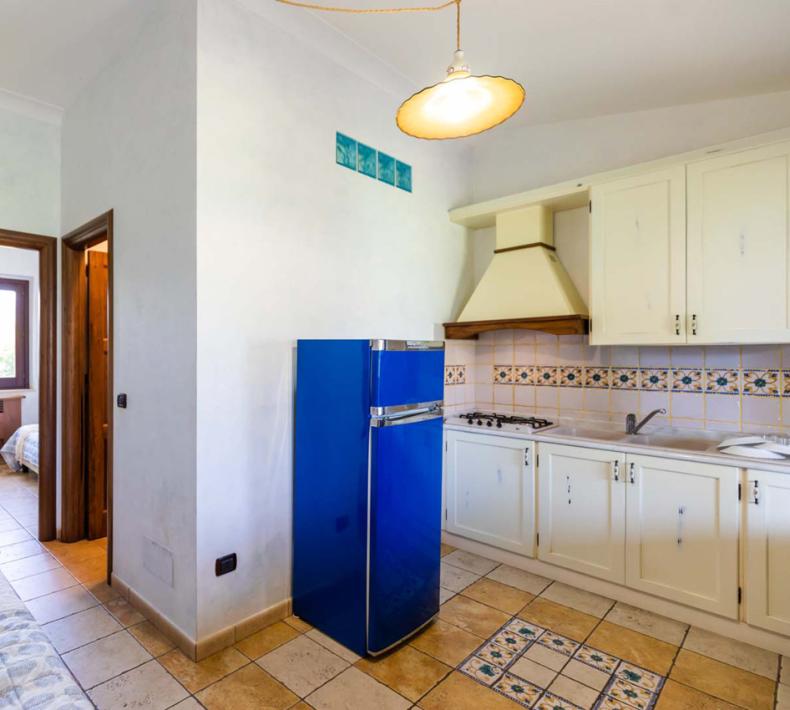 Helle Küche mit blauem Kühlschrank und Blick auf das Schlafzimmer.