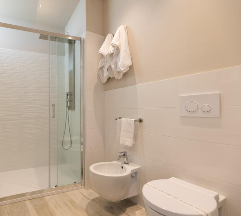 Modern bathroom with shower, bidet, and toilet. Towels hanging.