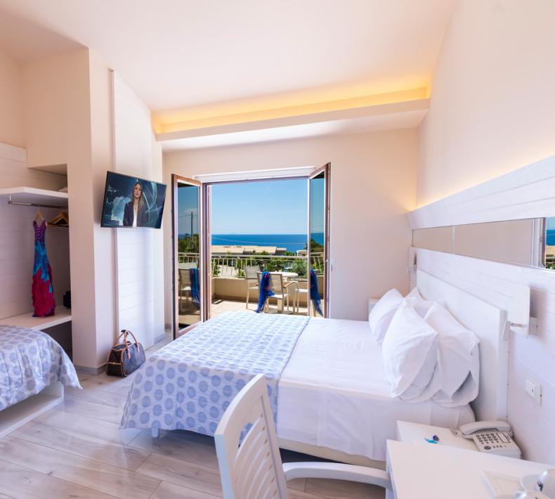 Bright room with sea view, two beds, TV, and balcony.