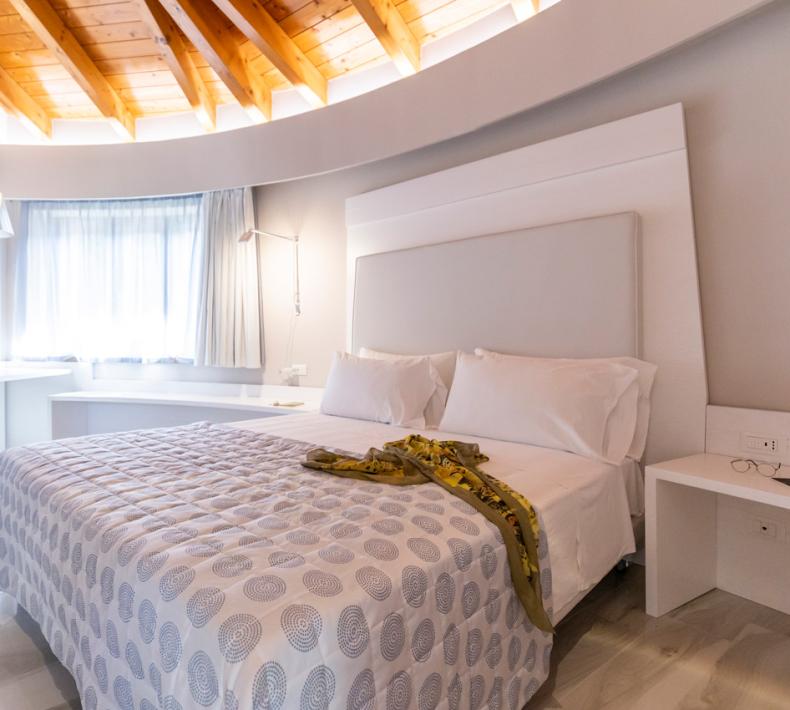 Chambre moderne avec plafond en bois et décoration blanche.