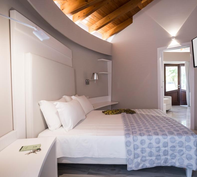 Modern bedroom with wooden ceiling and TV.