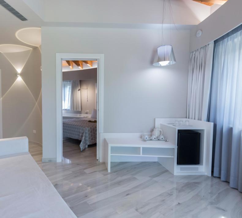 Chambre moderne avec canapé, lit et coin thé, décorée en blanc et bleu.