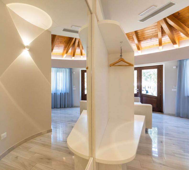 Ingresso luminoso con soffitto in legno e pareti curve.