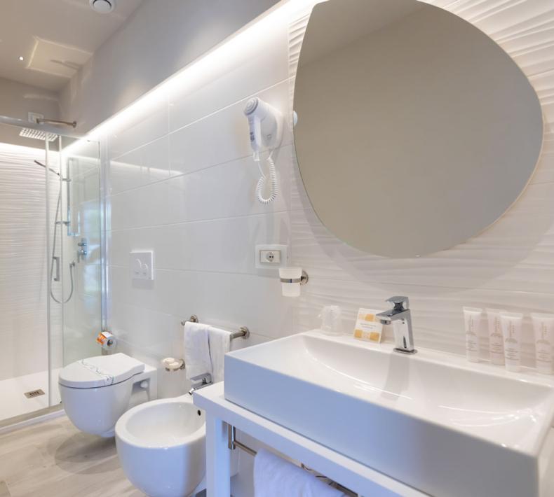 Bagno moderno con doccia, bidet, lavabo e specchio.