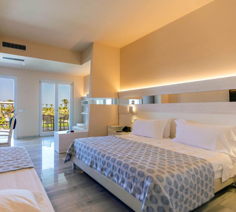 Chambre moderne avec lit double, TV et balcon avec vue.