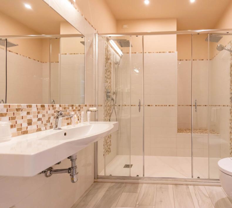 Salle de bain moderne avec double douche, lavabo suspendu et sol en bois.