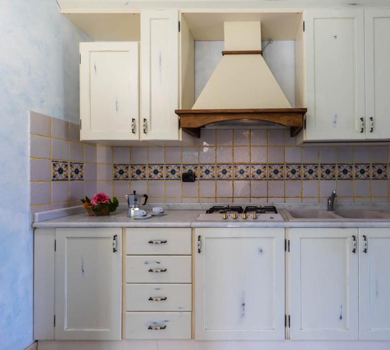 Rustikale Küche mit weißen Schränken und dekorativen Fliesen.