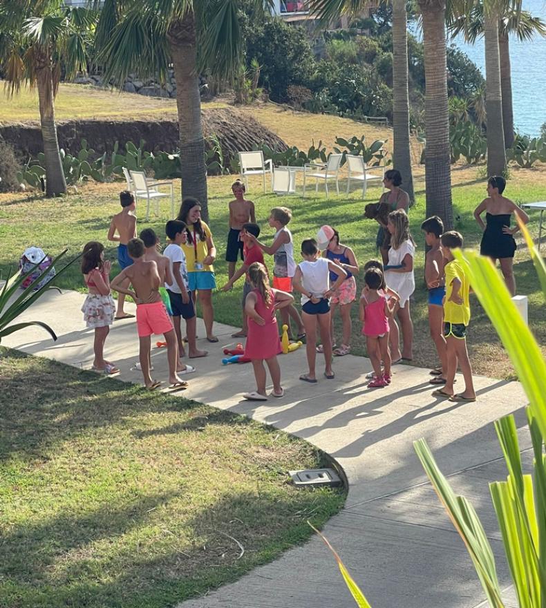 Bambini che giocano all'aperto sotto le palme vicino al mare.