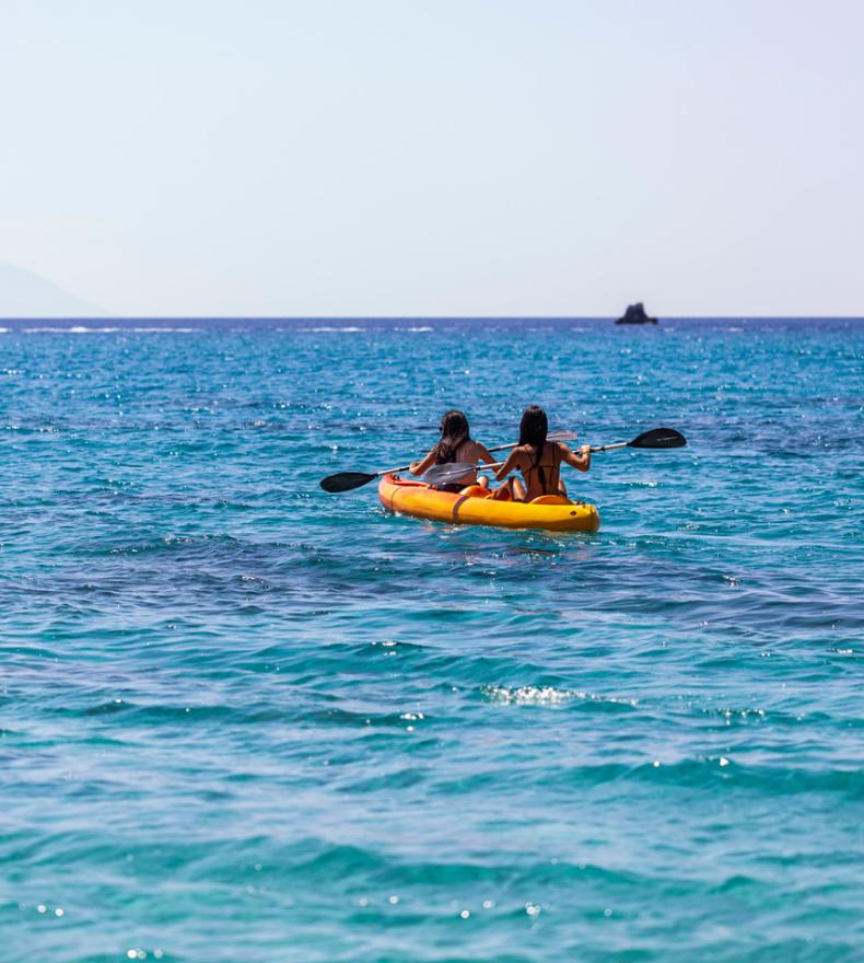 Two people kayaking on a crystal-clear sea.