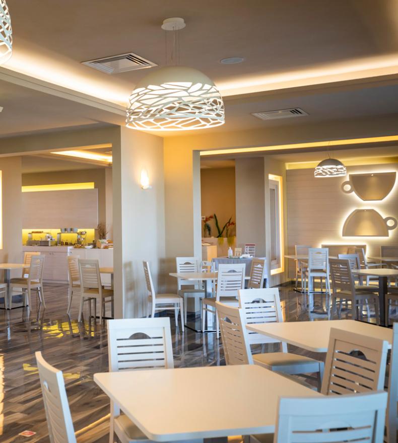 Moderno ristorante luminoso con arredi eleganti e illuminazione decorativa.