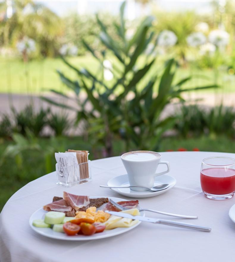 Outdoor breakfast with coffee, juice, fruit, pastries, and vegetables.