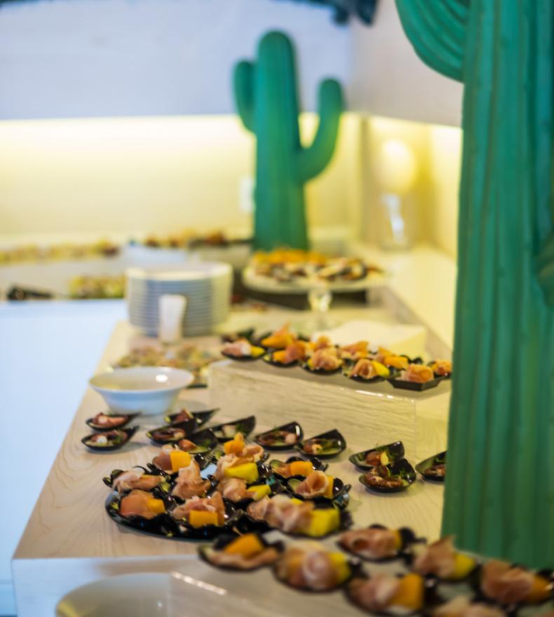 Buffet with food dishes and green cactus decorations.