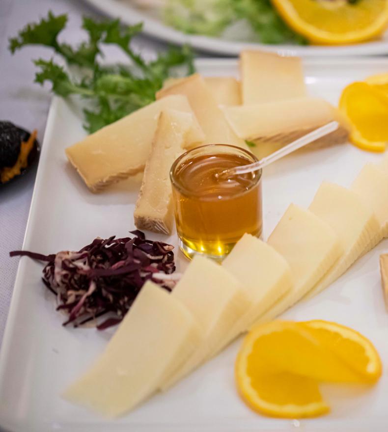 Cheese platter with honey, oranges, and vegetables.