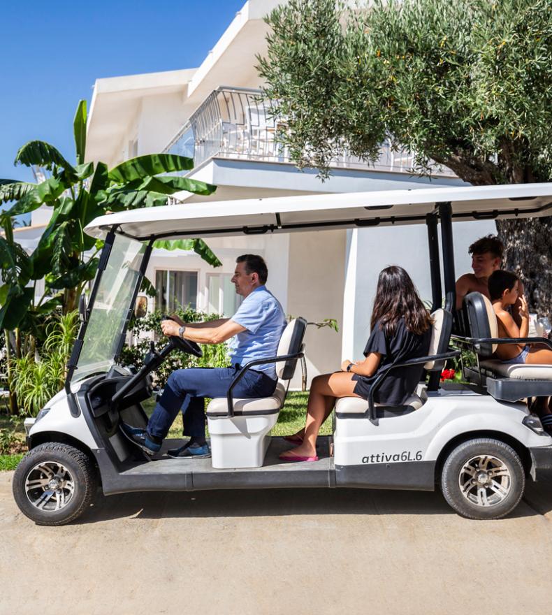 A golf cart with people in a tropical resort.